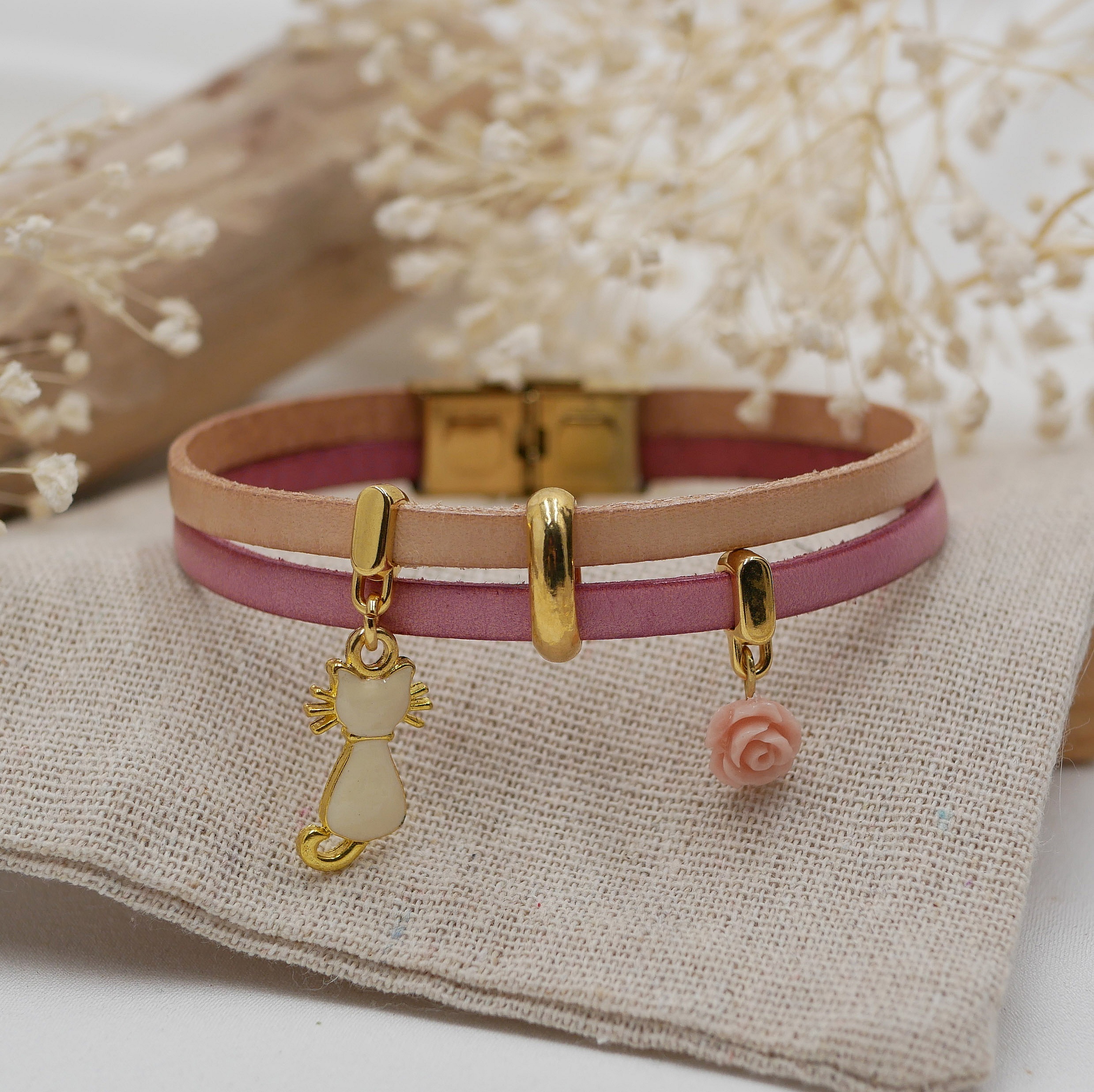 Bracelet duo en cuir avec breloques chat et rose dorées.