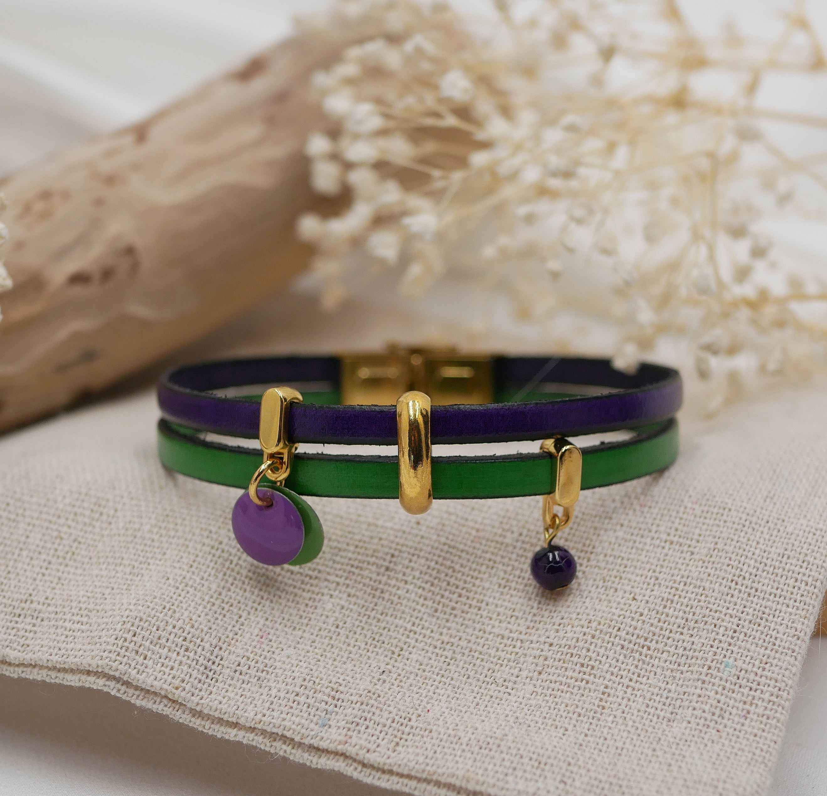 Bracelet duo en cuir violet et vert avec breloques dorées.