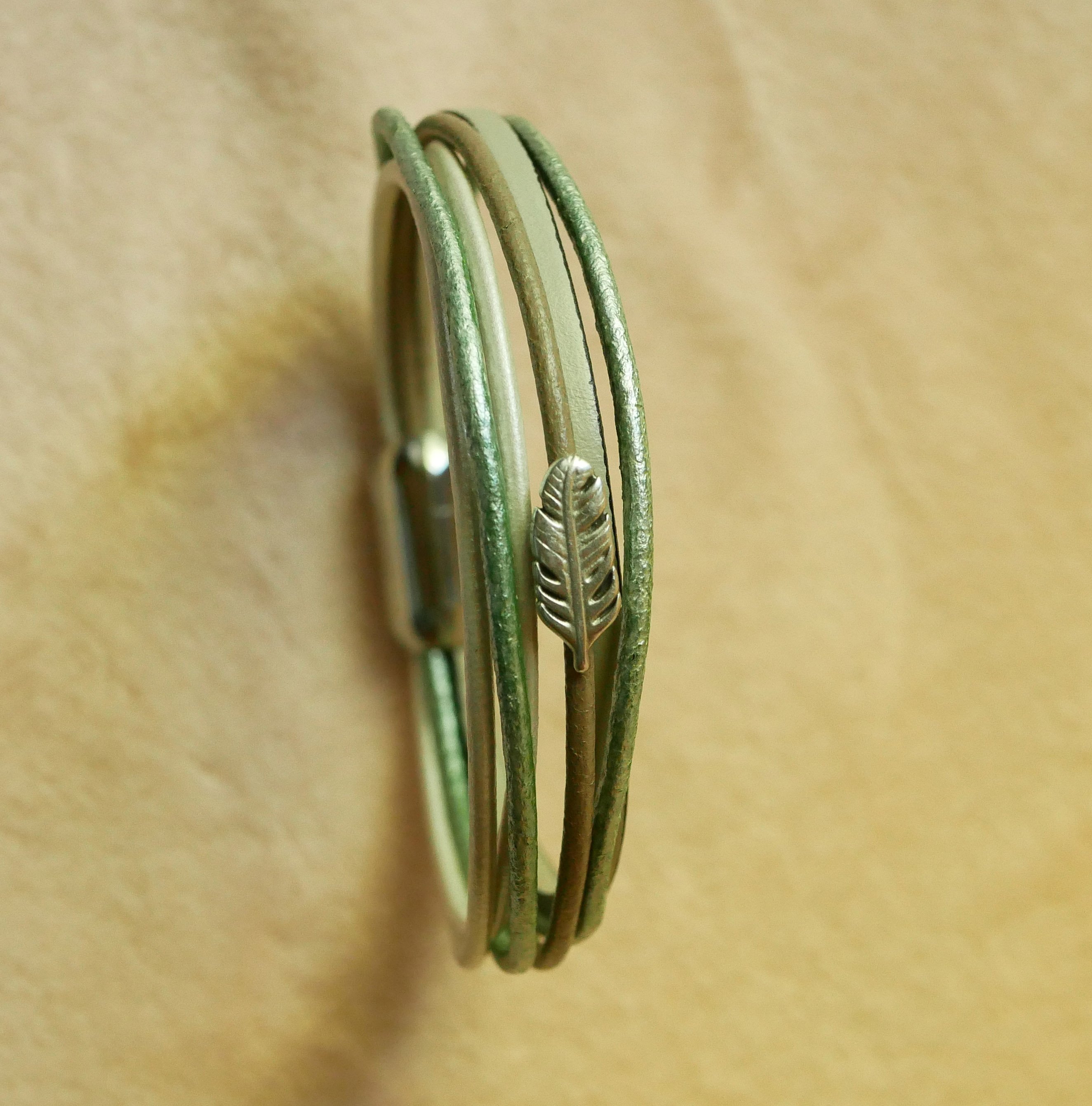 Multi-leather bracelet in shades of beige, pale green and pearly, decorated with a small feather