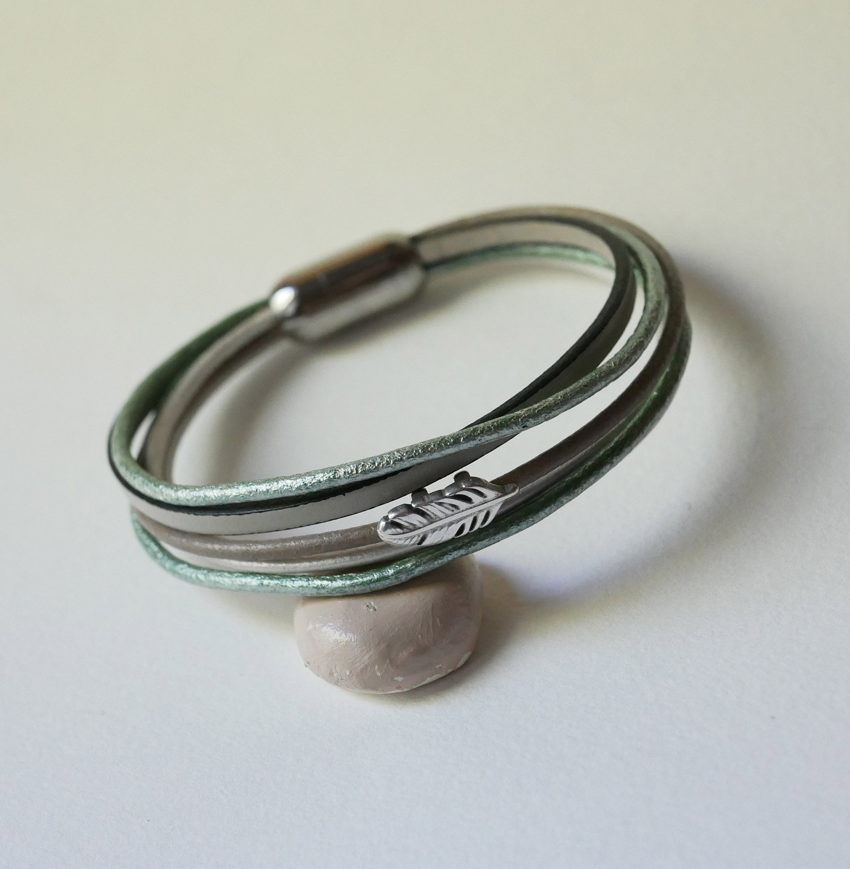 Multi-leather bracelet in shades of beige, pale green and pearly, decorated with a small feather