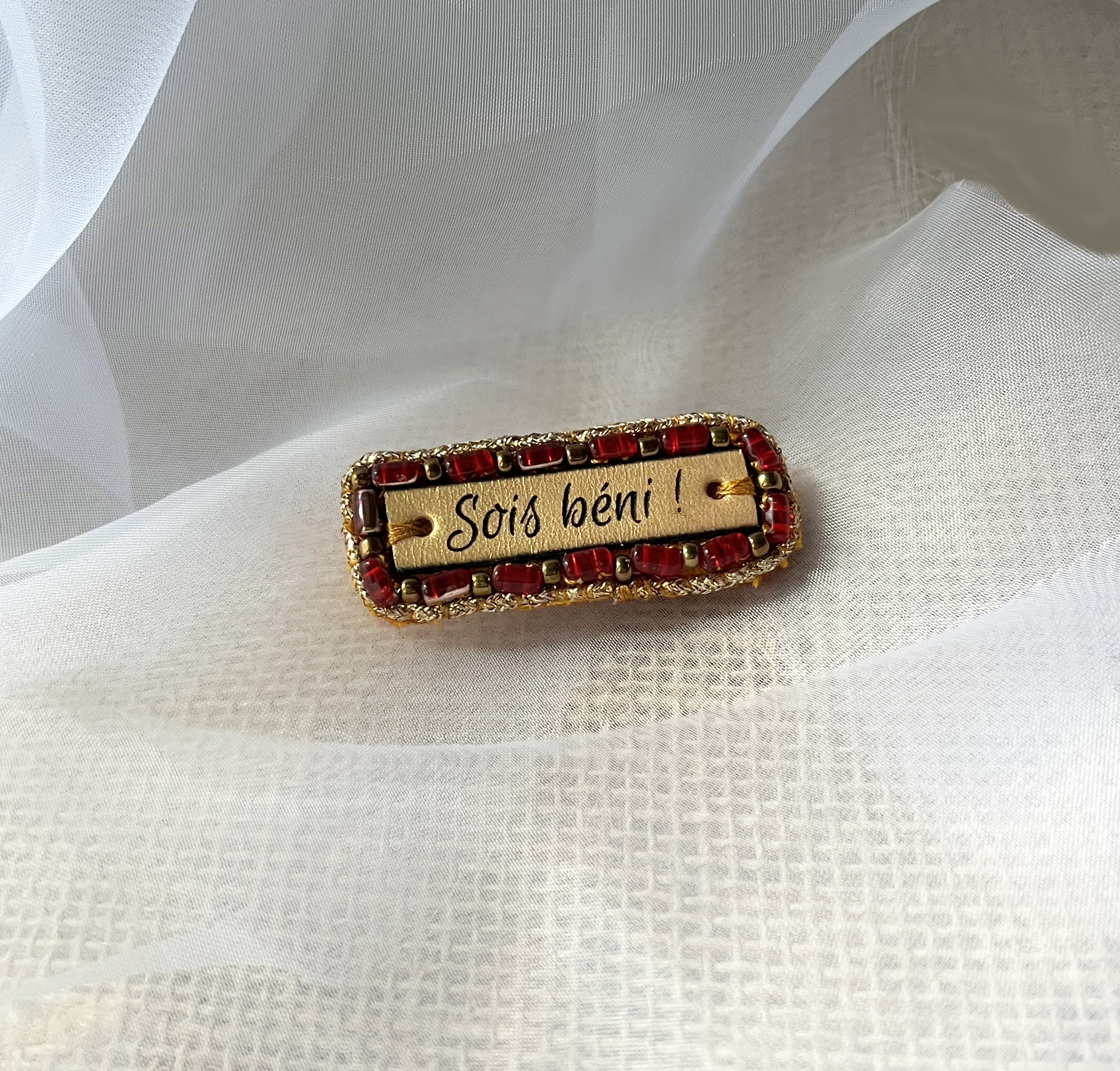 Broche à message en cuir gravé "sois béni" en perles rouges et dorées 