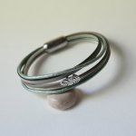 Multi-leather bracelet in shades of beige, pale green and pearly, decorated with a small feather